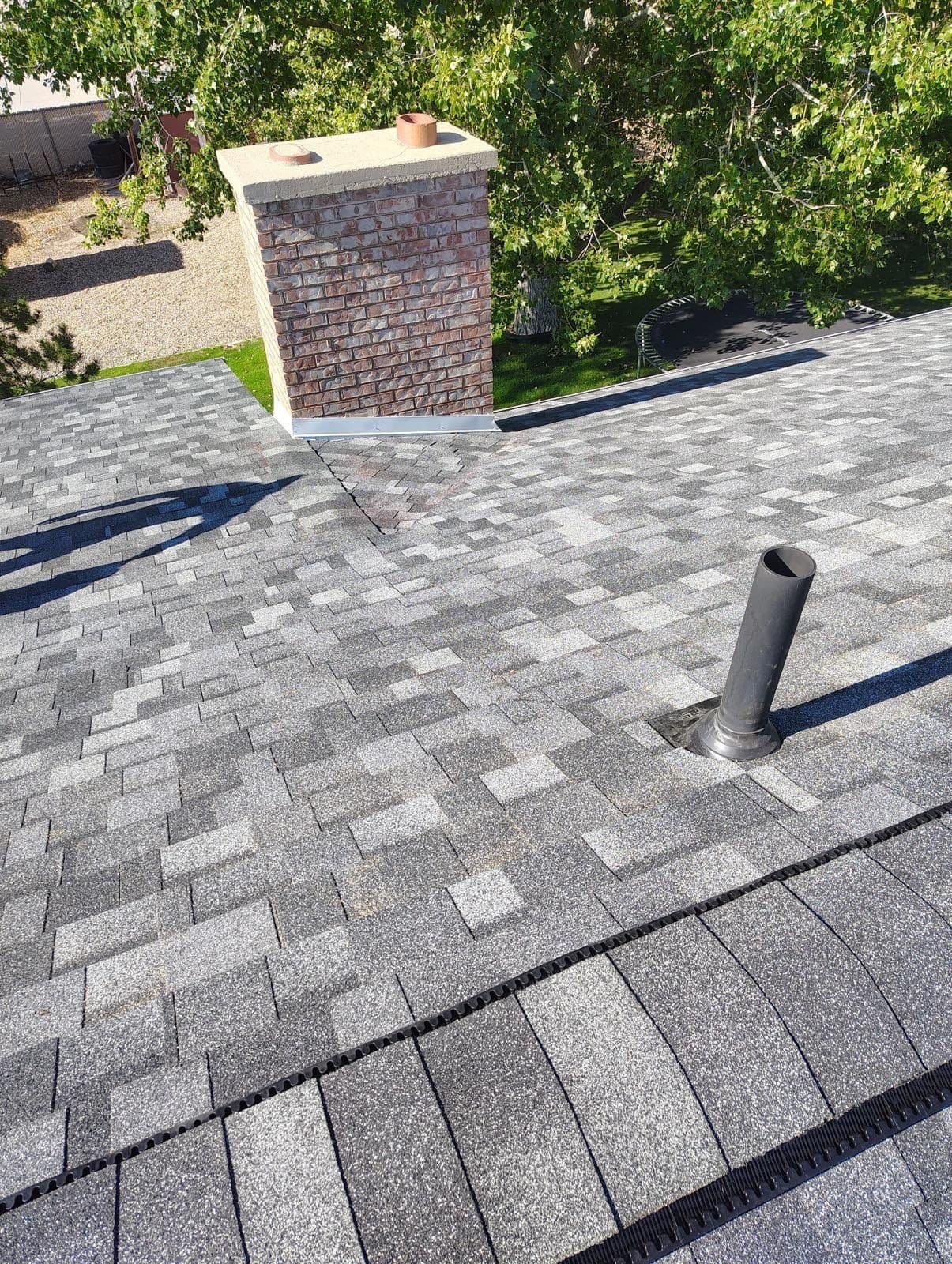 Finished grey architectural shingle roof with chimney