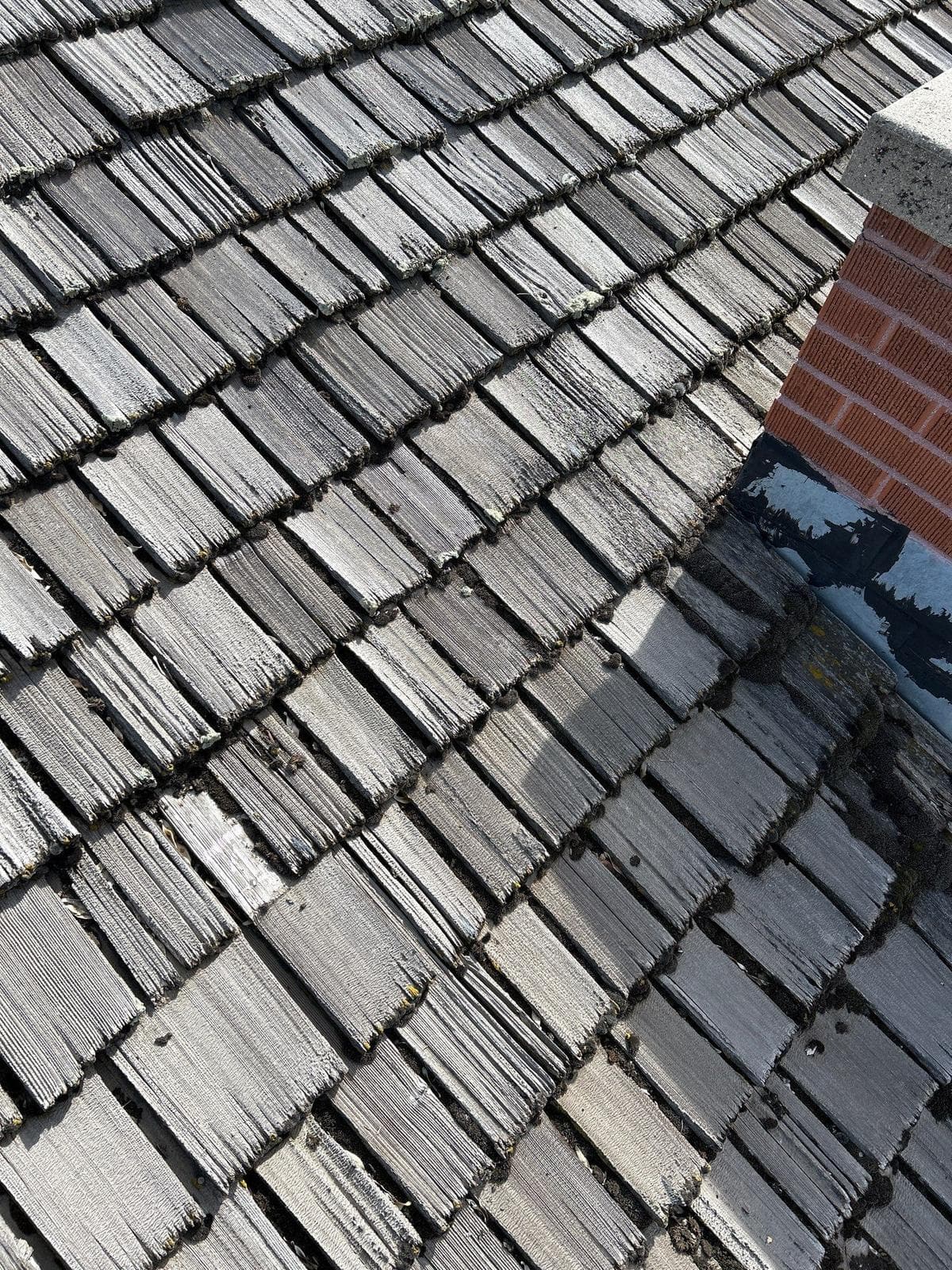 Weathered gray cedar shake running up to a brick chimney on a Provo home