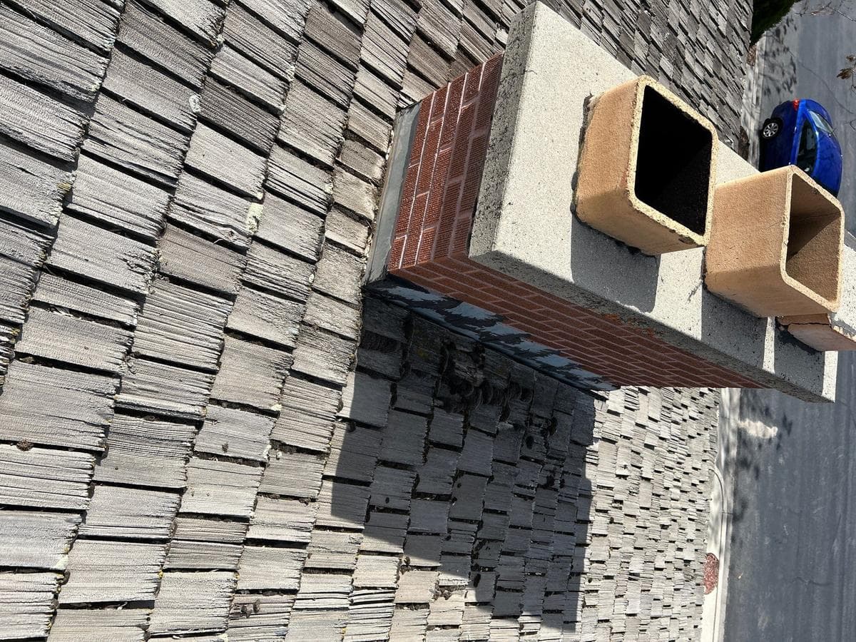 Cedar shake meeting the brick chimney before the tear-off