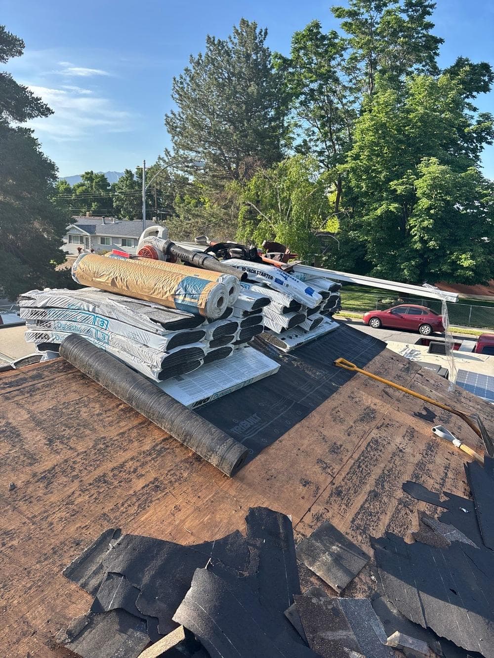 Tear-off underway with underlayment and shingle bundles staged